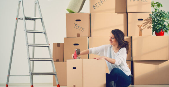 Young Caucasian girl using duct tape for packing carton boxes